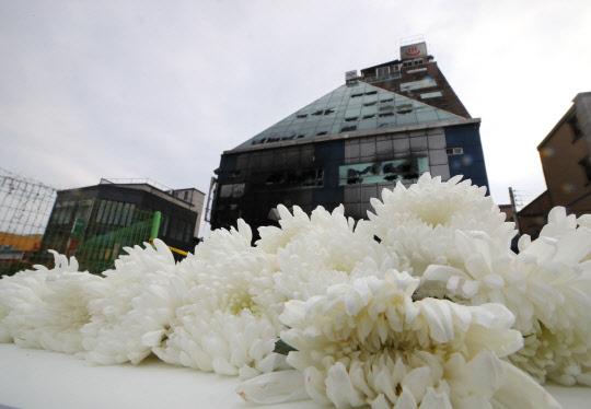 안타까움만 가득히...  22일 오후 화재로 대형 참사가 벌어진 충북 제천 스포츠센터 화재현장에 피해자를 추모하는 흰 국화꽃들이 상처투성이의 건물을 배경으로 안타까움을 더하고 있다.  2017.12.22